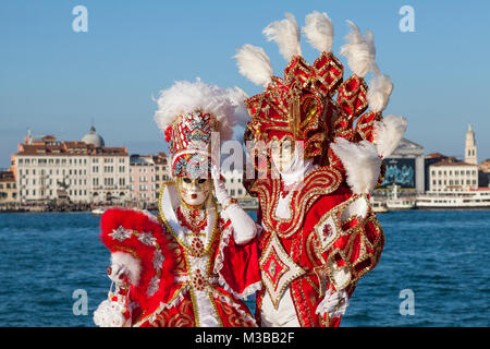 Venice, Veneto, Italy, 10th February 2018. Colourful costumes at the Venice Carnival on a sunny day on the last weekend of the festival. People posing on San Giorgio Maggiore Island at sunset. Stock Photo