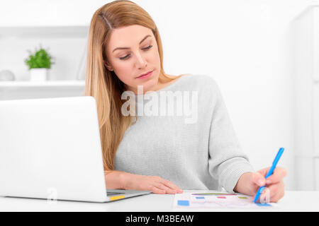 Attractive young lady working with graphics at the table with laptop. Stock Photo