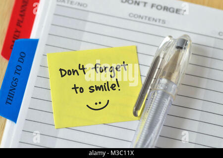 Text don't forget to smile written on a sticky note over an agenda background Stock Photo