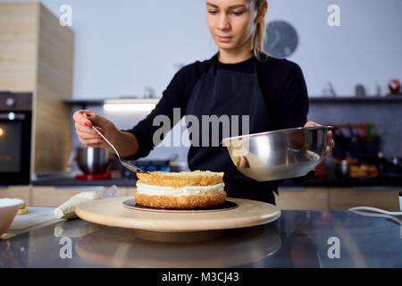 A confectioner woman makes  cake in the kitchen. Stock Photo