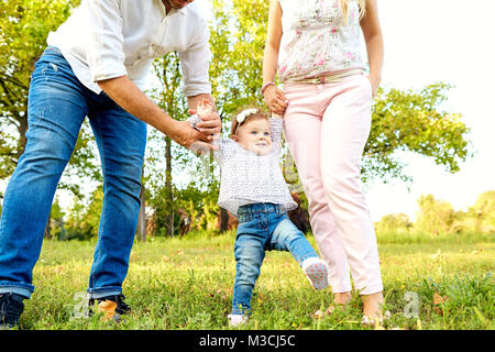 The first steps of the baby. Parents are teaching their child to Stock Photo