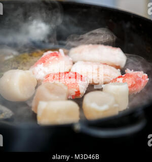 A few pieces of deep-sea scallop and several pieces of crab meat are fried in a pan Stock Photo