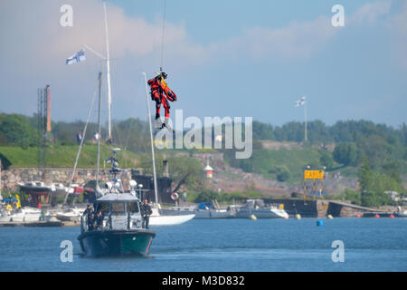 Helsinki, Finland - 9 June 2017: Unidentified Finnish Coast Guard rescue swimmer drops down to the Baltic Sea be a wire in rescue exercise or performa Stock Photo