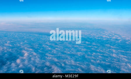 Aerial View of Dense Clouds From Airplane Window With Light from Left Stock Photo