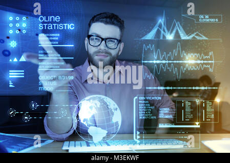 Young smart programmer pointing to the transparent screen and looking confident Stock Photo