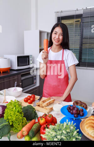 woman holding a carrot in kitchen room Stock Photo