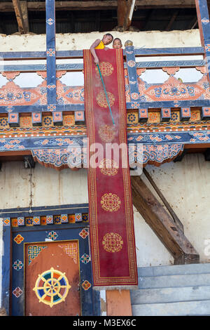 Phobjikha, Bhutan.  Young Monk Dusting a Floor Carpet, Gangte Monastery (Goemba). Stock Photo