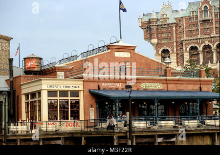 Vintage American building on a pier with large awning and benches in front. Back right is tall building. Old water tower on roof back left. Disneysea. Stock Photo