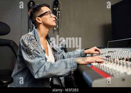 Busy female audio engineer working in recording studio Stock Photo