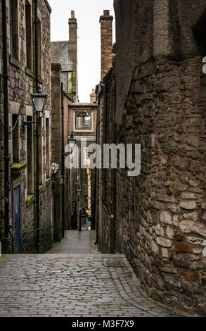 View down Anchor Close, alley off Royal Mile, High Street, Edinburgh, Scotland, UK, with old fashioned Victorian street lights and cobbled pavement Stock Photo