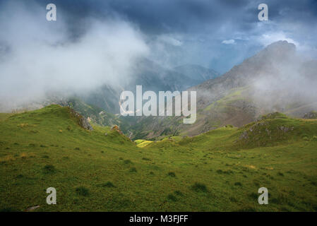 Joggly grassy slope, mountain view, low clouds Stock Photo