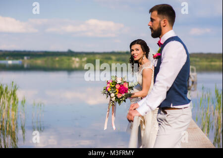 Beautiful wedding couple staying on the small bringe under the water Stock Photo