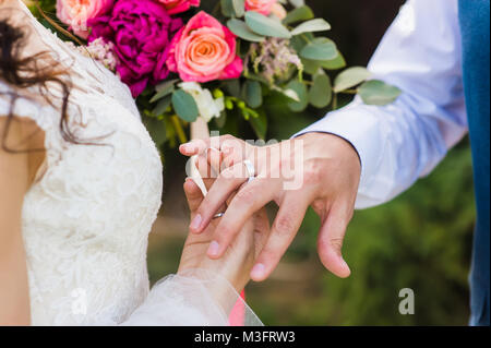 Couple exchange their wedding rings during ceremony closeup picture outdoors Stock Photo