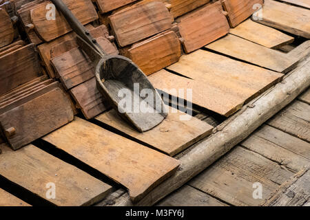construction industry concept, old roofing tile and shovel on wooden floor Stock Photo