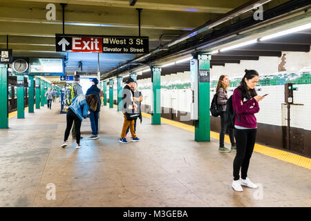 New York City, USA - October 28, 2017: People walking standing waiting in underground transit empty large platform in NYC Subway Station, exit sign at Stock Photo