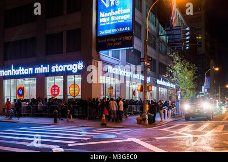 New York City, USA - October 28, 2017: NYC downtown dark evening night illuminated Vandam street road with traffic cars, people standing waiting in li Stock Photo