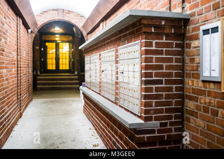 Brick apartment building entrance in downtown NYC New York City with mailbox post mail boxes, empty corridor in evening night with nobody, secured are Stock Photo