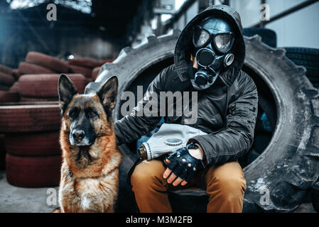 Stalker in gas mask and dog, friends in post apocalyptic world. Post-apocalypse lifestyle on ruins, doomsday, judgment day Stock Photo