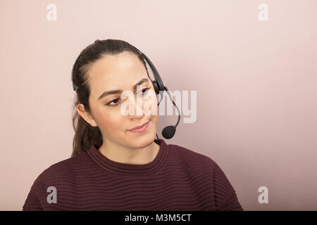 Dark-haired woman sitting with headset in call center in a concept of customer services, call center or telesales Stock Photo