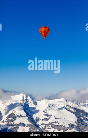 40th International Hot Air Balloon Festival in Château-d´Oex - balloons are flying in the blue sky over the swiss mountain scenery Stock Photo