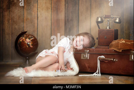 A child in a retro interior and an old phone sits on the floor.  Stock Photo