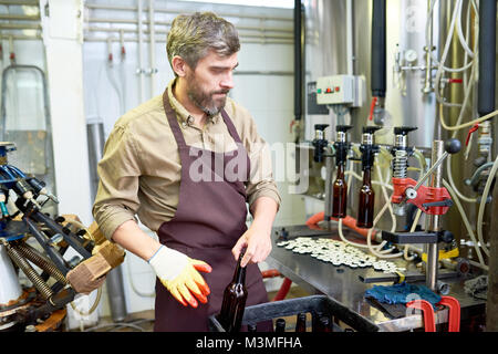 Confident beer factory worker putting bottles in box Stock Photo