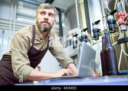 Thoughtful bearded technician holding examination at brewery Stock Photo