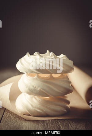 Stack of three meringue nests on parchment roll on table Stock Photo
