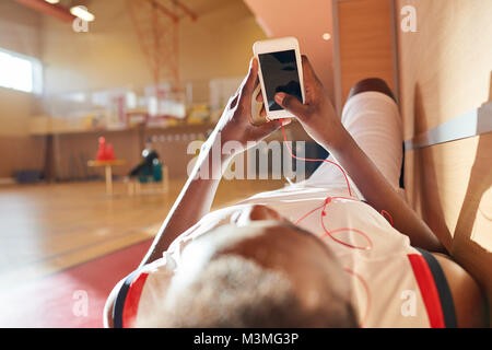 African sportsman listening to music in earphones on bench Stock Photo