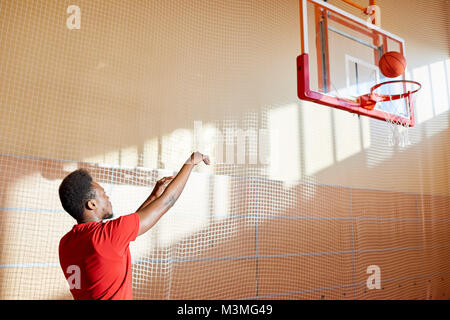 Skilled young basketball player training on court