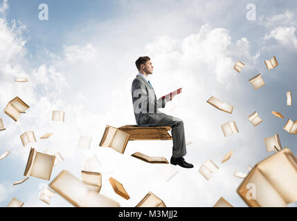 Man reading book and many of them flying in air Stock Photo