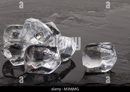 Ice cubes on black slate board with drops of water Stock Photo