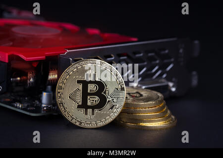 cryptocurrency mining concept with golden bitcoin coins next to a computer performant video card black background Stock Photo