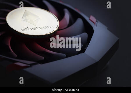 cryptocurrency mining concept with one golden Ethereum coin on top of a computer performant video card black fan Stock Photo