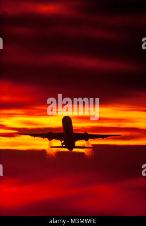 A jet commercial airliner takes off and climbs into a colorful dawn sky Stock Photo