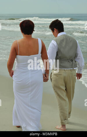 Married Couple Holding Hands and Walking on the Beach Stock Photo