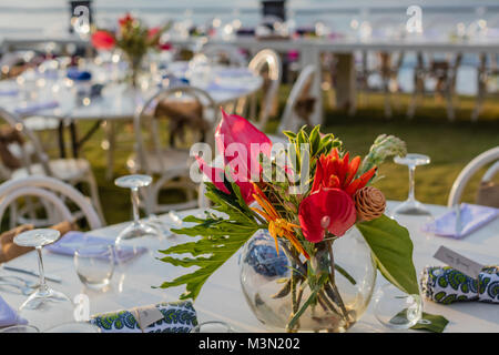 Tables set up for a wedding reception party, decorated with bouquets of tropical flowers. Stock Photo