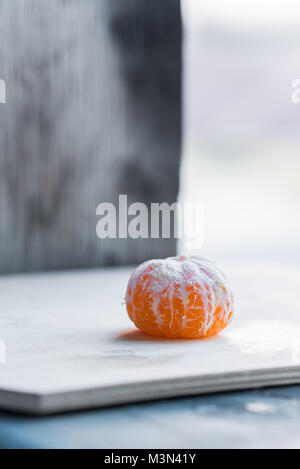 Studio shot of whole tangerine without peel on white wooden board, healthy organic food concept Stock Photo