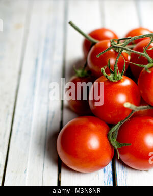 Tomatoes on the vine on rustic wooden table background Stock Photo - Alamy