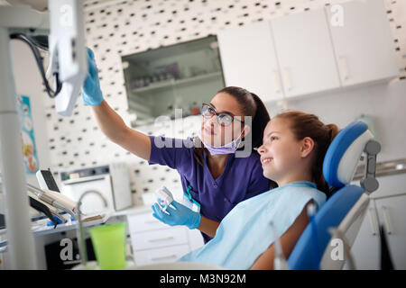 Dentist female shows on x-ray footage to young patient her problem with teeth Stock Photo