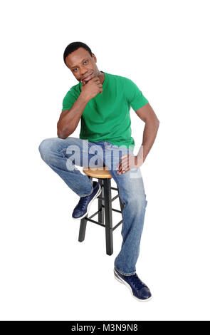 A full body image on a African American man in jeans and green shirt sitting on chair with his hand on the chin, isolated for white background Stock Photo