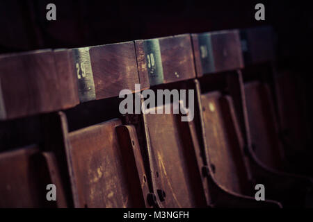 A row of hard, wooden chairs in the stands of an old football stadium in England. Stock Photo