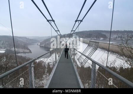 Wendefurth, Germany - February 10,2018: A woman crosses the longest pedestrian rope bridge in the world. It is located at the Rappbode dam in the Harz Stock Photo