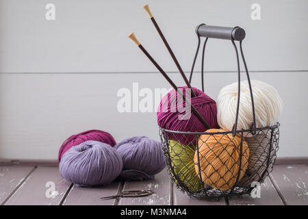 Colorful spring wool yarn in an iron basket with wooden knitting needles. With a copyspace Stock Photo