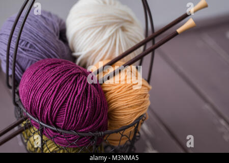 Colorful spring wool yarn in an iron basket with wooden knitting needles. With a copyspace Stock Photo