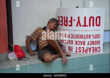 21.01.2018, Singapore, Republic of Singapore, Asia - An elderly man leans on a wall and a signpost in Singapore's Chinatown district and takes a nap. Stock Photo