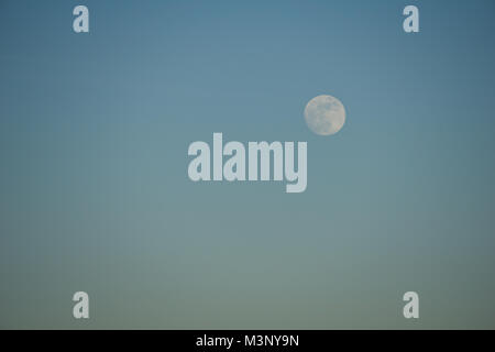 Full moon visible in the evening sky just before sunset Stock Photo