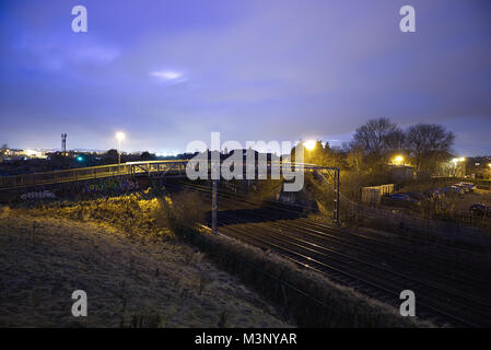 A night shot of the Glasgow-Edinburgh trainline with a pedestrian bridge in the Saughton area of Edinburgh, Scotland Stock Photo