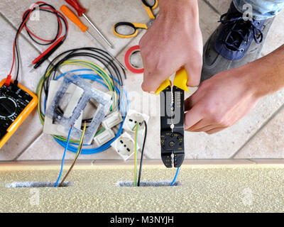 Electrician technician at work uses the wire stripper in a residential electrical installation Stock Photo