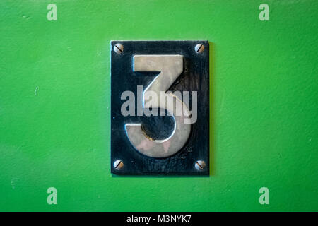 number 3 sign - number three metal sign on green background - Stock Photo